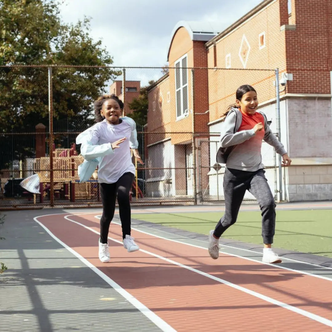 Two children running outdoors beside a school building